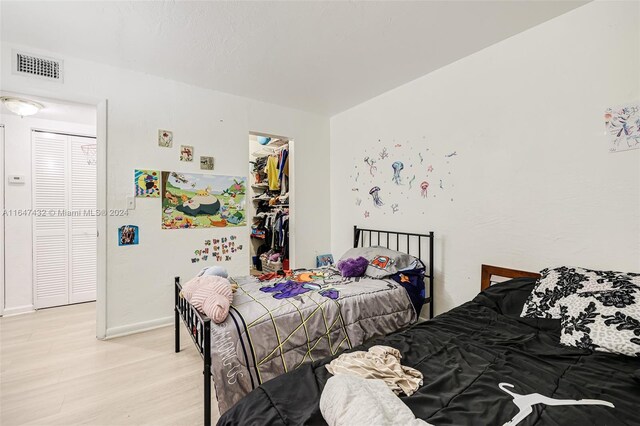 bedroom with a walk in closet, a closet, and wood-type flooring