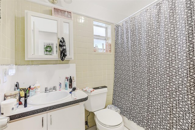 bathroom featuring a shower with shower curtain, toilet, vanity, and tile walls