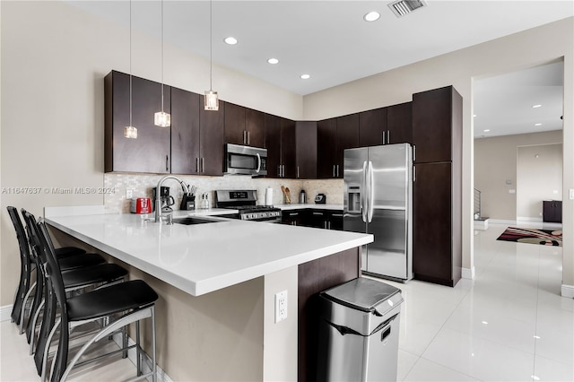 kitchen featuring stainless steel appliances, a breakfast bar, decorative backsplash, and decorative light fixtures