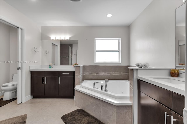 bathroom featuring tile patterned floors, vanity, tiled bath, and toilet