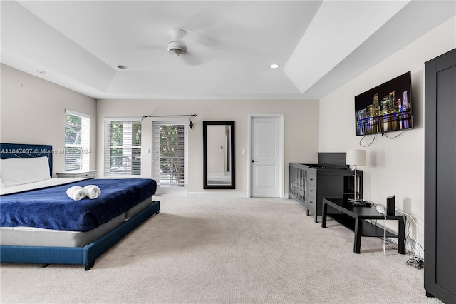 bedroom with a tray ceiling, ceiling fan, and light carpet