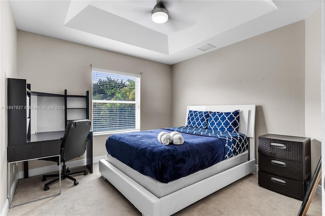 carpeted bedroom with ceiling fan and a raised ceiling