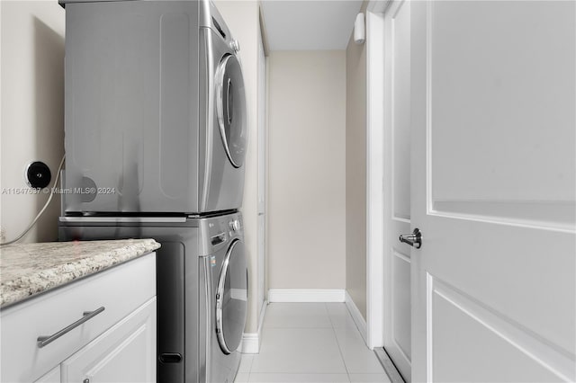 washroom with stacked washer and clothes dryer, cabinets, and light tile patterned floors