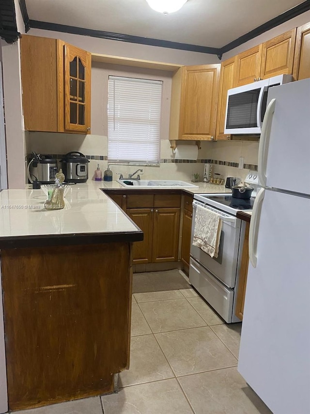 kitchen with light tile patterned floors, white appliances, sink, tasteful backsplash, and kitchen peninsula