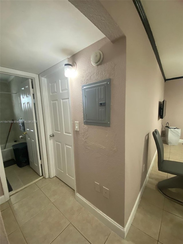 hallway with crown molding, electric panel, and light tile patterned flooring