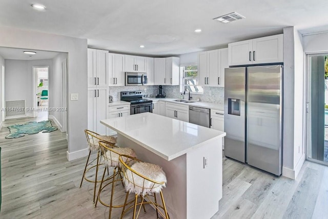 kitchen with a kitchen bar, white cabinetry, sink, and stainless steel appliances