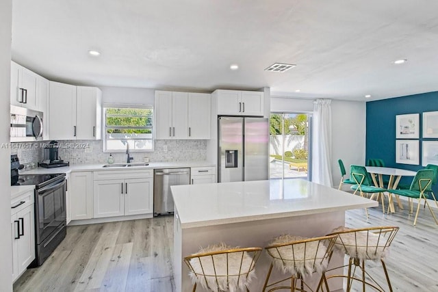 kitchen with white cabinets, appliances with stainless steel finishes, plenty of natural light, and sink