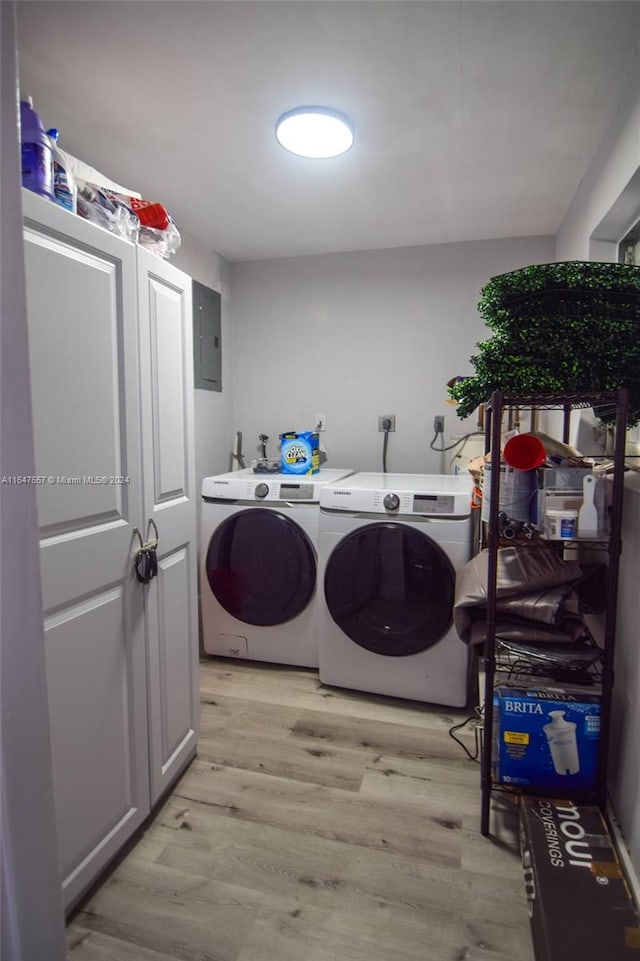 laundry area with washing machine and clothes dryer, electric panel, and light hardwood / wood-style flooring