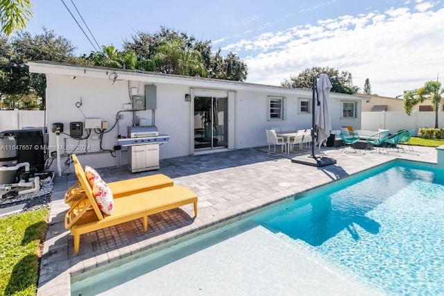 rear view of property with a fenced in pool and a patio