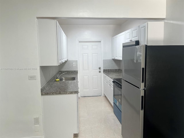 kitchen featuring sink, decorative backsplash, stainless steel refrigerator, light tile patterned floors, and white cabinets