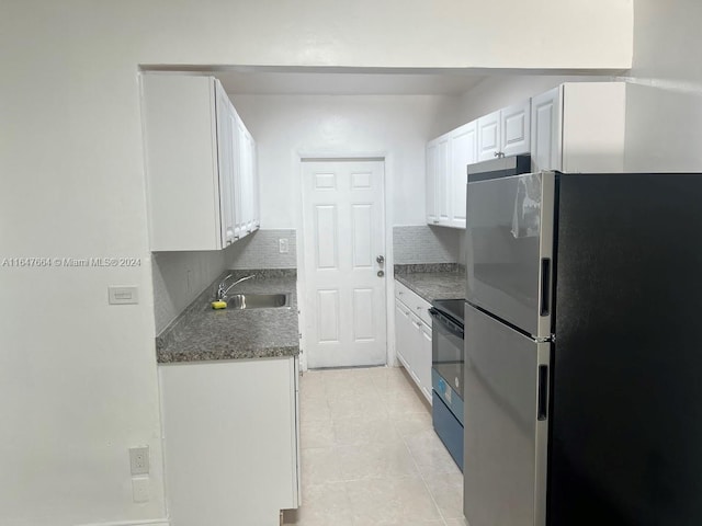 kitchen featuring sink, black / electric stove, stainless steel refrigerator, tasteful backsplash, and white cabinets