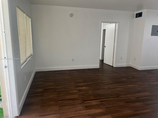 spare room with dark wood-type flooring, electric panel, and a healthy amount of sunlight