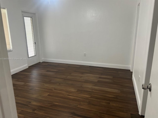 unfurnished room with dark wood-type flooring