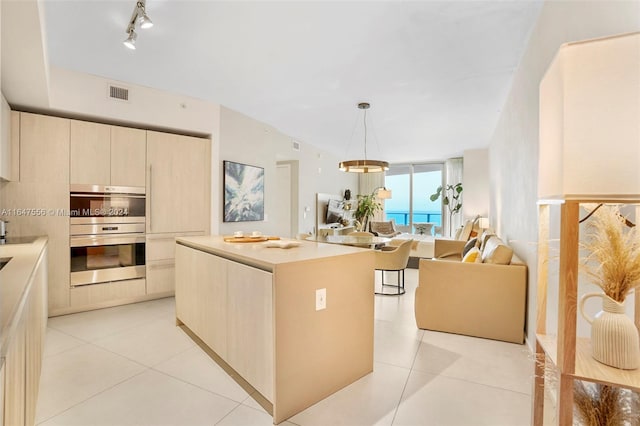 kitchen with track lighting, double oven, light tile patterned floors, a kitchen island, and hanging light fixtures