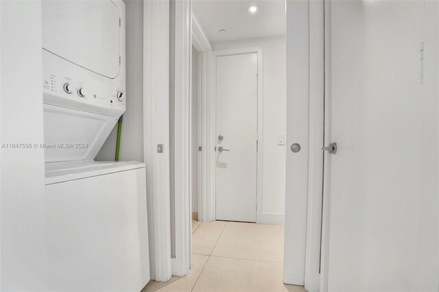 hallway with stacked washer / dryer and light tile patterned floors