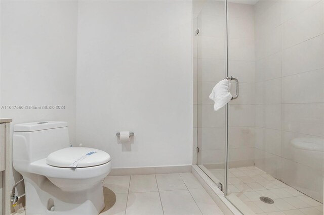 bathroom featuring toilet, tile patterned floors, and a shower with door