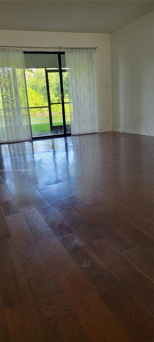 spare room featuring a textured ceiling and dark wood finished floors