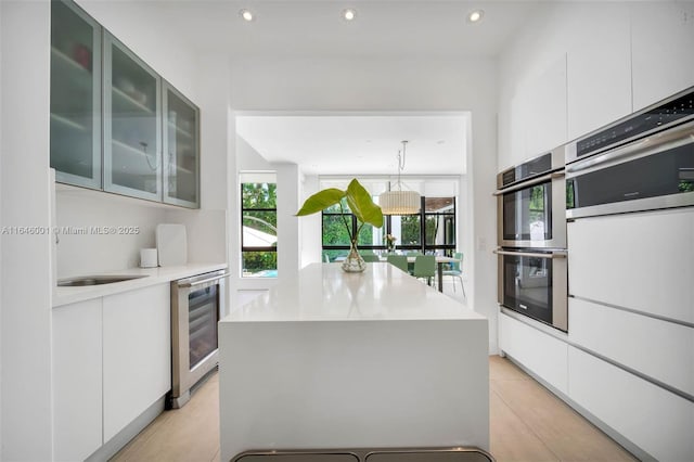 kitchen featuring wine cooler, stainless steel double oven, modern cabinets, and light countertops