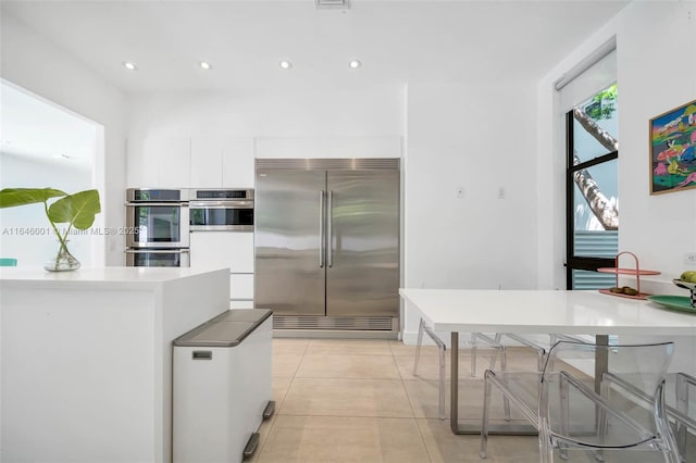 kitchen featuring light countertops, light tile patterned floors, recessed lighting, stainless steel appliances, and white cabinetry