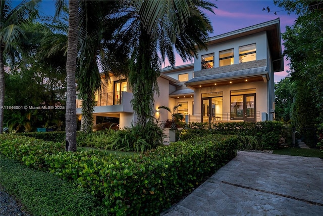 back of property at dusk featuring stucco siding