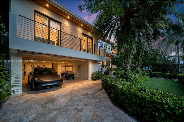 view of front facade featuring a carport, decorative driveway, a garage, and stucco siding