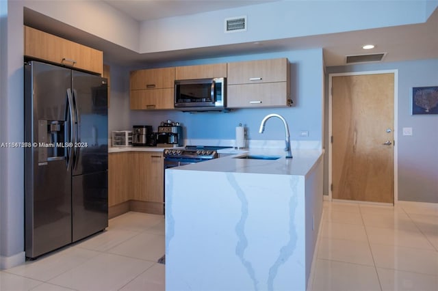 kitchen featuring light brown cabinets, light tile patterned flooring, appliances with stainless steel finishes, and sink