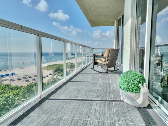 balcony featuring a view of the beach and a water view