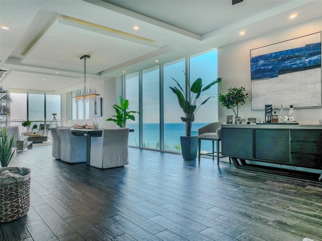 living room with a wall of windows, a notable chandelier, a water view, and dark hardwood / wood-style flooring