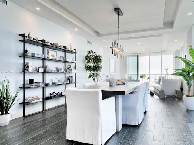 dining area featuring expansive windows, a tray ceiling, and dark wood-type flooring