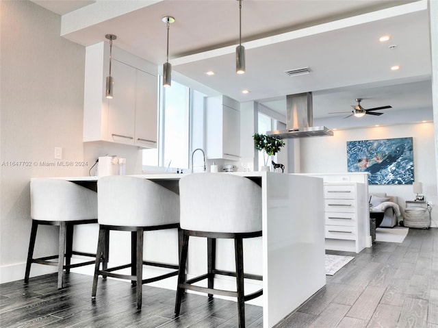 kitchen featuring a kitchen breakfast bar, dark wood-type flooring, white cabinetry, and exhaust hood