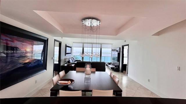 tiled dining room featuring a tray ceiling and a chandelier