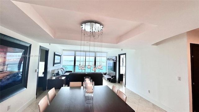 dining area featuring a raised ceiling, light tile patterned floors, and an inviting chandelier