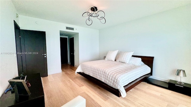 bedroom featuring light hardwood / wood-style floors and a chandelier