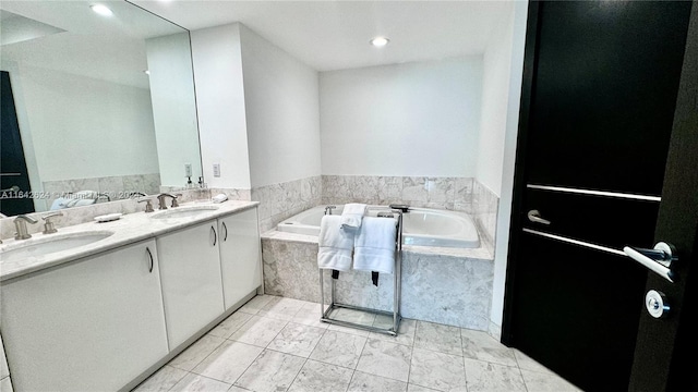 bathroom featuring tile patterned floors, vanity, and a relaxing tiled tub