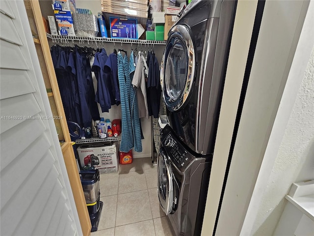 laundry area featuring stacked washer / drying machine and light tile patterned floors