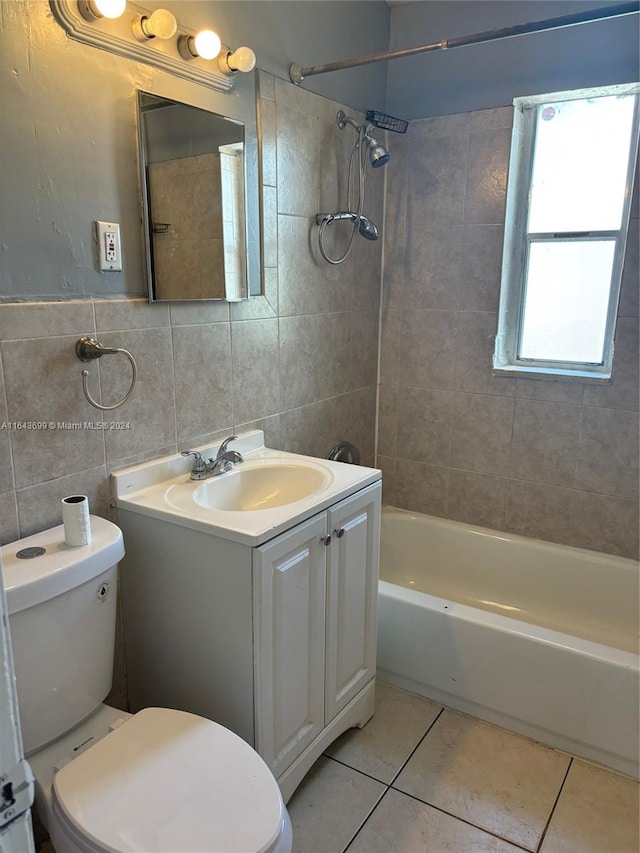 full bathroom with tiled shower / bath, tile patterned floors, vanity, tile walls, and toilet