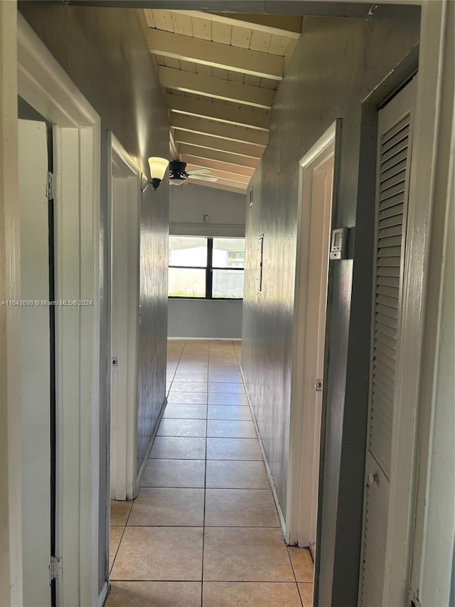 corridor featuring light tile patterned floors and vaulted ceiling with beams