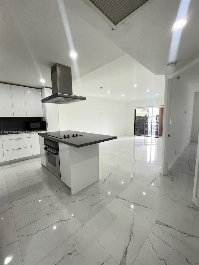 kitchen featuring black electric stovetop, wall chimney exhaust hood, stainless steel oven, white cabinetry, and a kitchen island