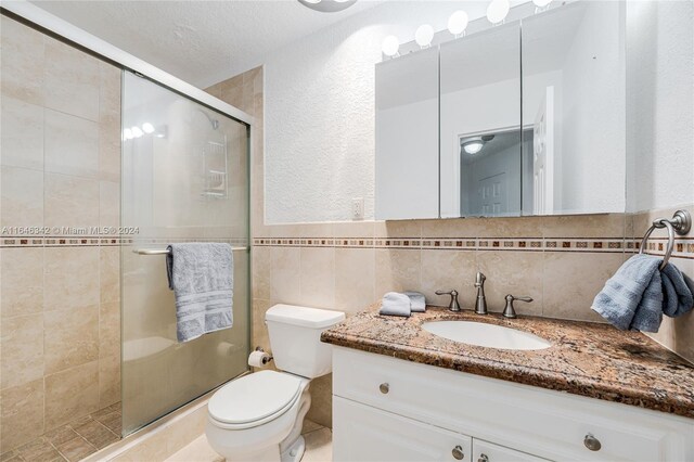 bathroom with tasteful backsplash, toilet, vanity, and a shower with shower door