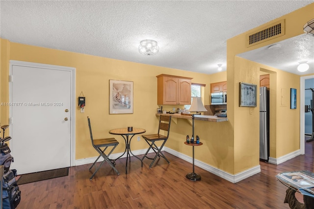 dining area with visible vents, baseboards, a textured ceiling, and dark wood-style floors