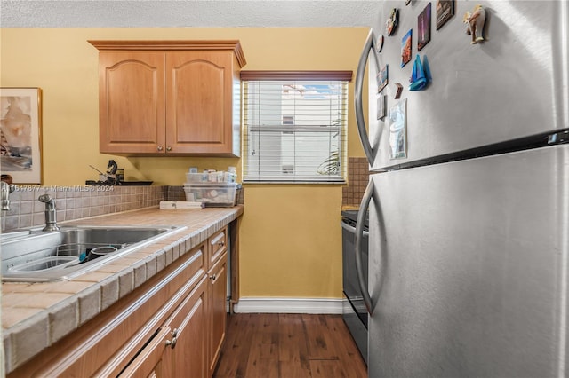 kitchen featuring sink, dark hardwood / wood-style flooring, tile counters, tasteful backsplash, and stainless steel appliances