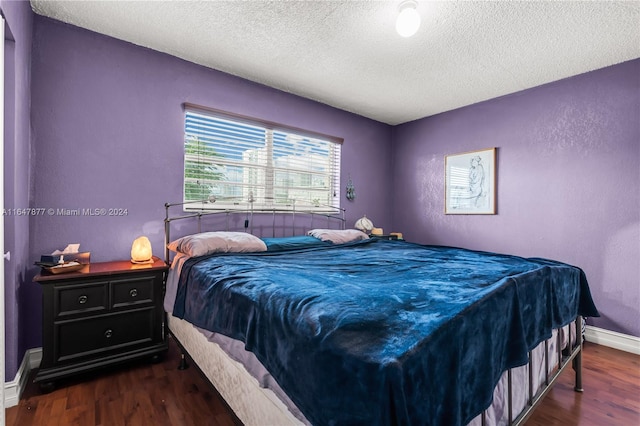 bedroom with dark hardwood / wood-style flooring and a textured ceiling