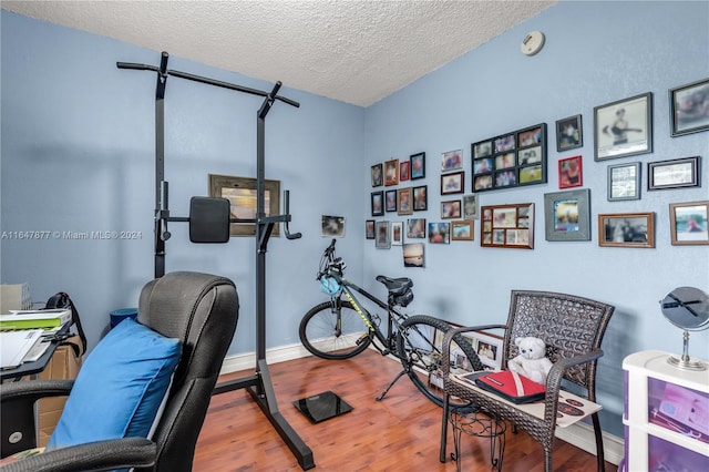 workout room featuring wood finished floors, baseboards, and a textured ceiling