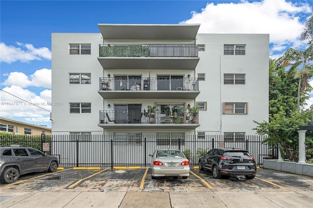 view of building exterior featuring uncovered parking and fence