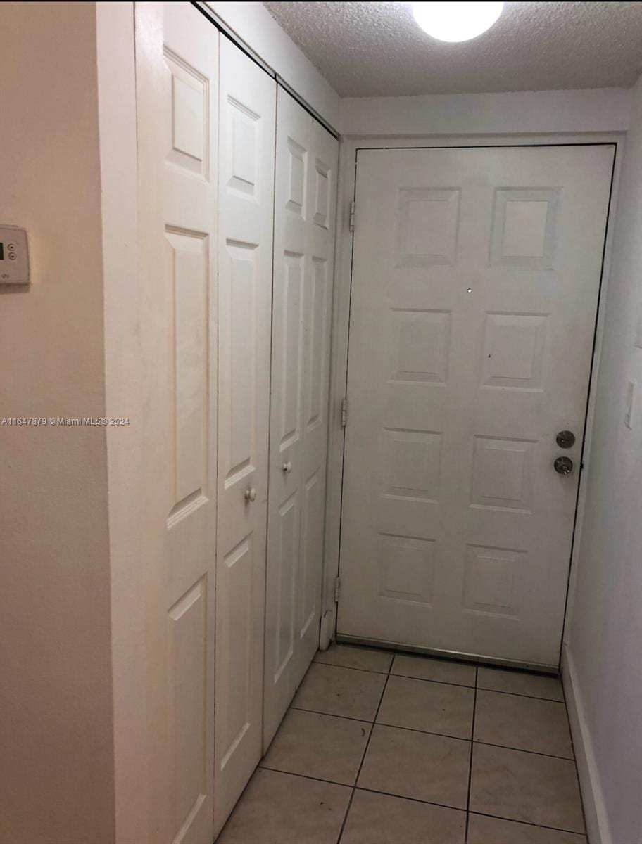 doorway featuring a textured ceiling and light tile patterned floors