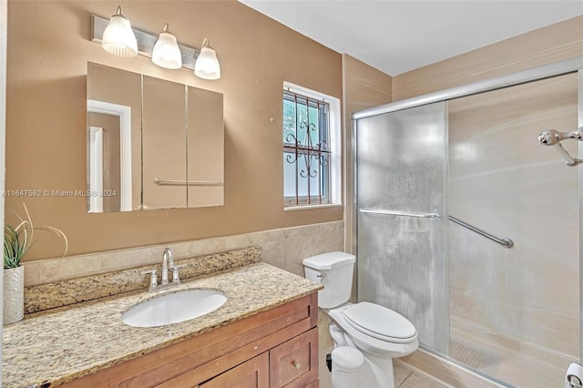 bathroom featuring toilet, an enclosed shower, vanity, and tile walls