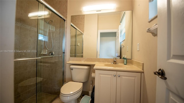 bathroom featuring vanity, toilet, and a shower with shower door