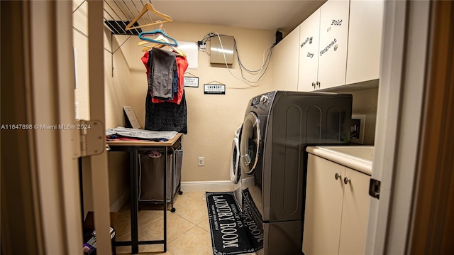 laundry area featuring light tile patterned flooring, cabinets, and washer and dryer