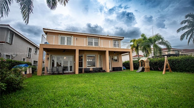 rear view of house featuring a lawn and a balcony