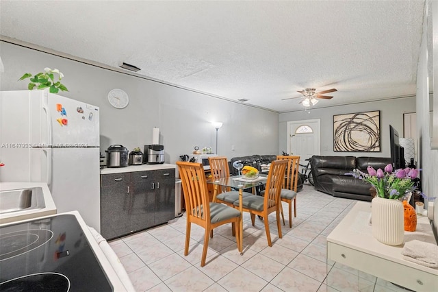 tiled dining room with a textured ceiling and ceiling fan